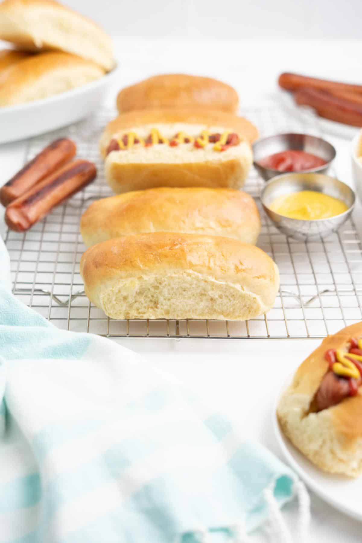 Homemade hot dog buns, hot dogs, and condiments on a table.