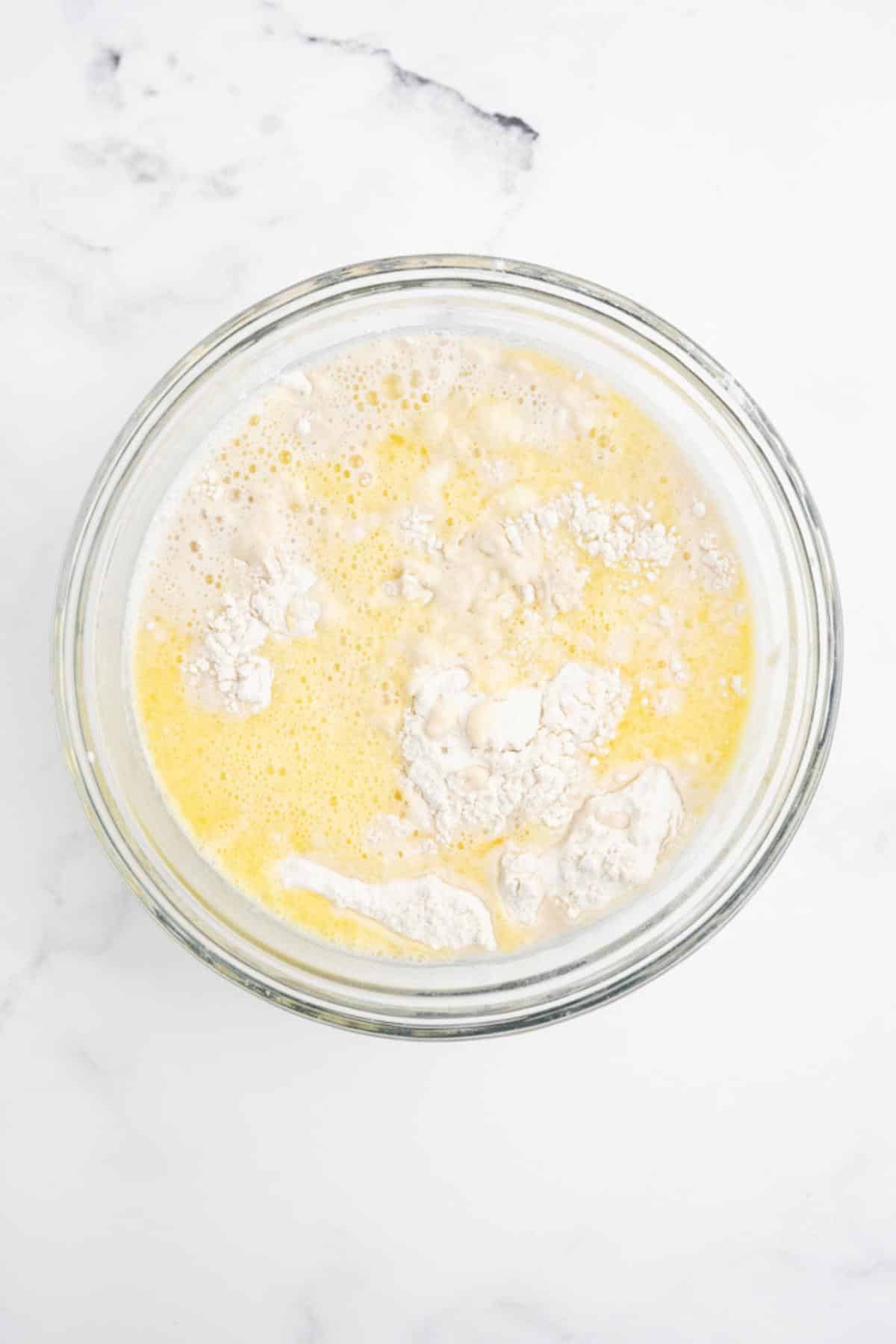 Flour added to the bowl of wet ingredients.