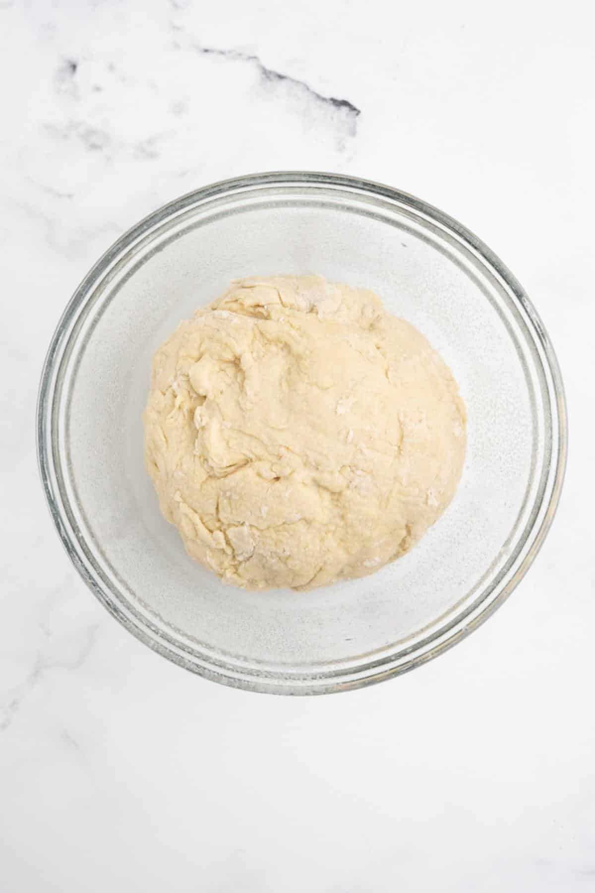 Dough shaped into a rough ball in a bowl.