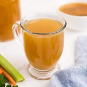 A cup of slow cooker rotisserie chicken broth on a table.