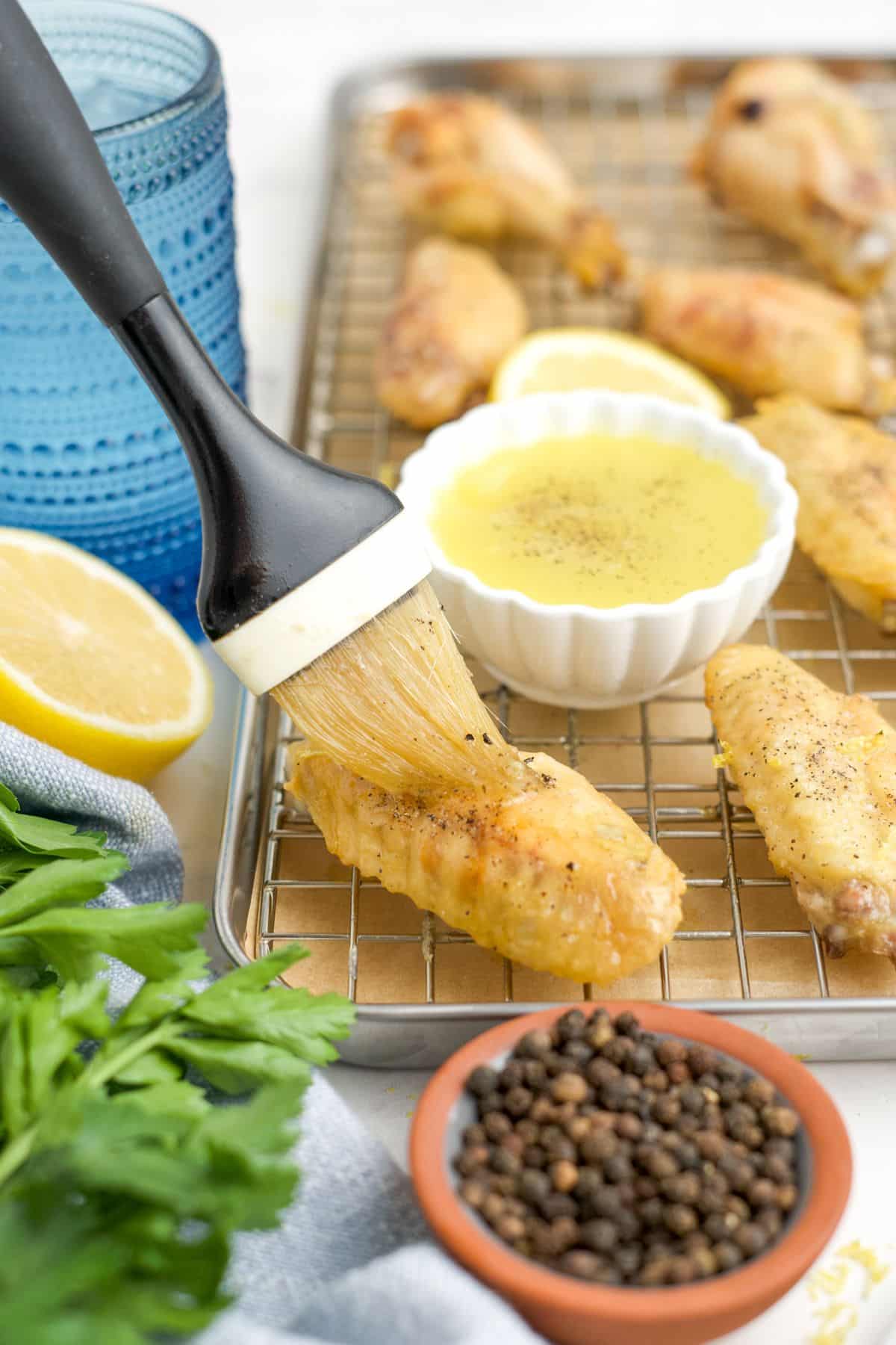 Brushing lemon pepper sauce on a chicken wing.