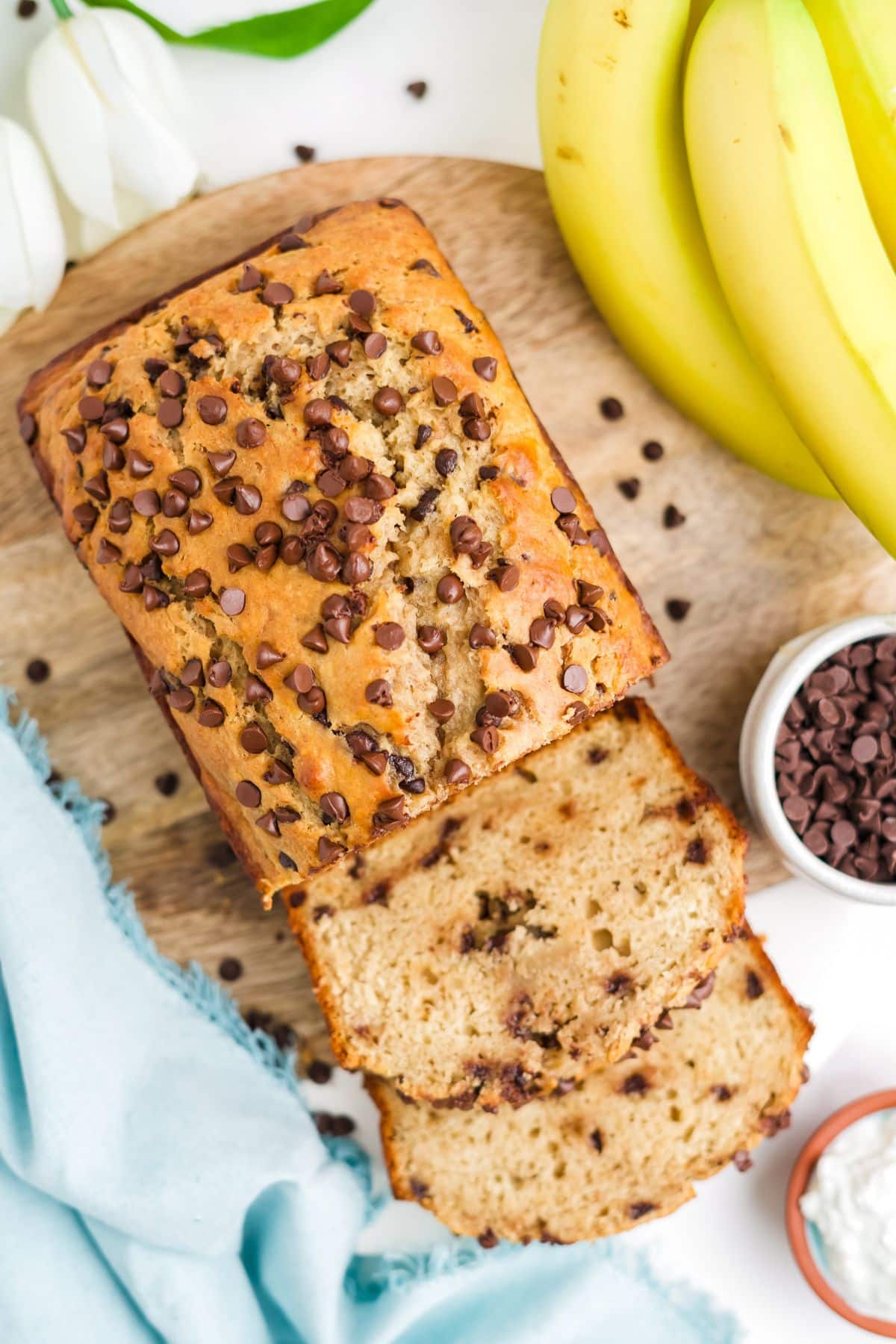 Protein banana bread on a wooden cutting board with some slices leaning over.