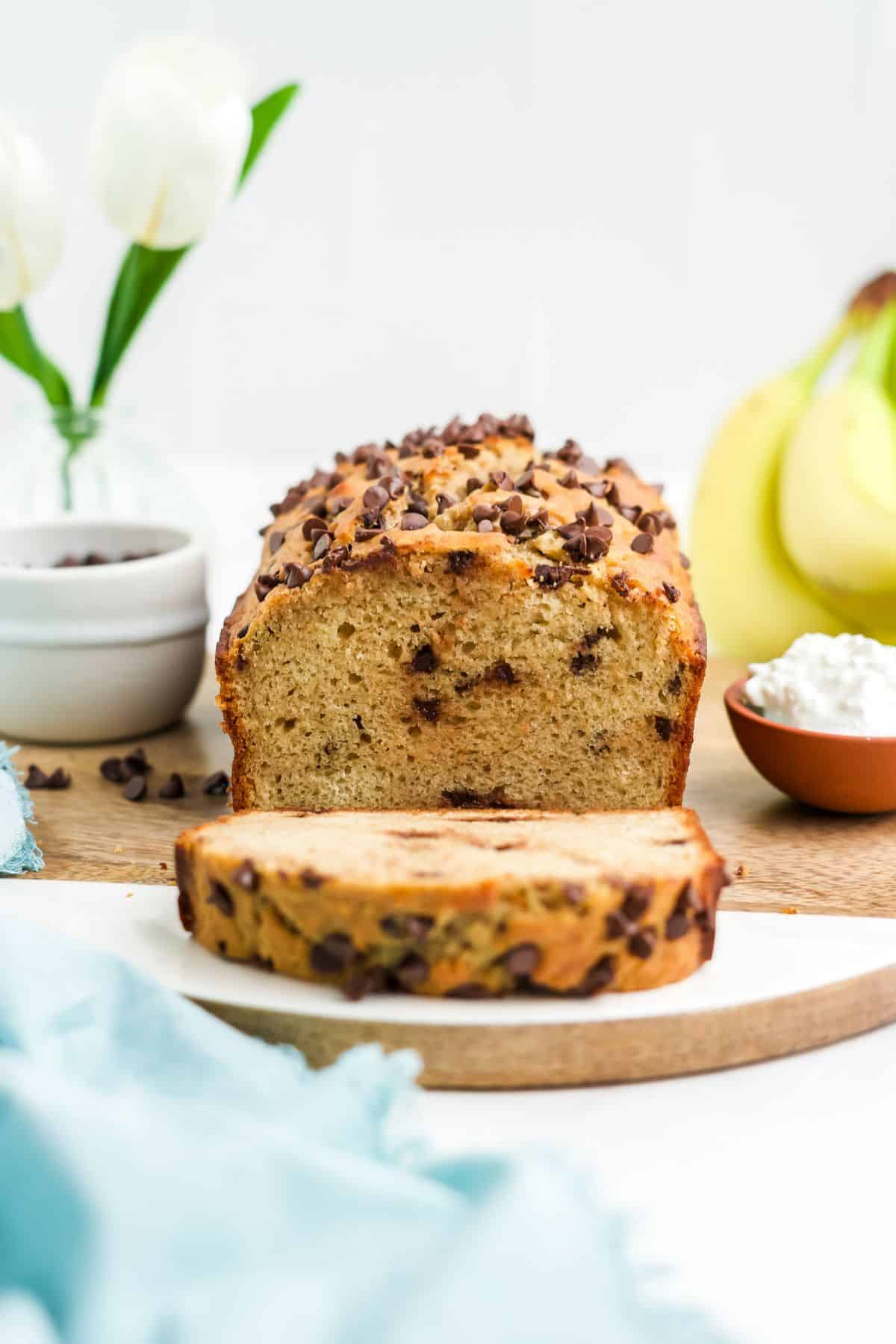 Cottage cheese banana bread on a cutting board with some slices cut and leaning over in front.