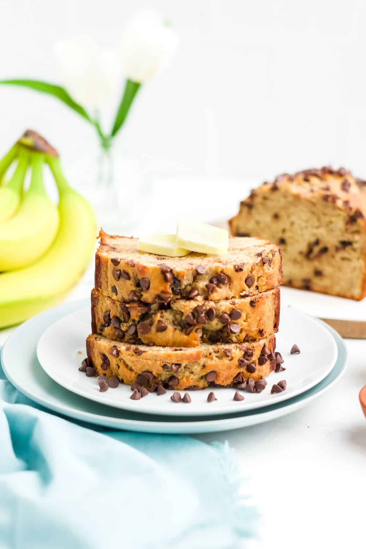 A stack of three slices of cottage cheese banana bread topped with pats of butter.