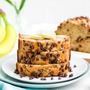 A stack of sliced cottage cheese banana bread on a plate with butter on top.