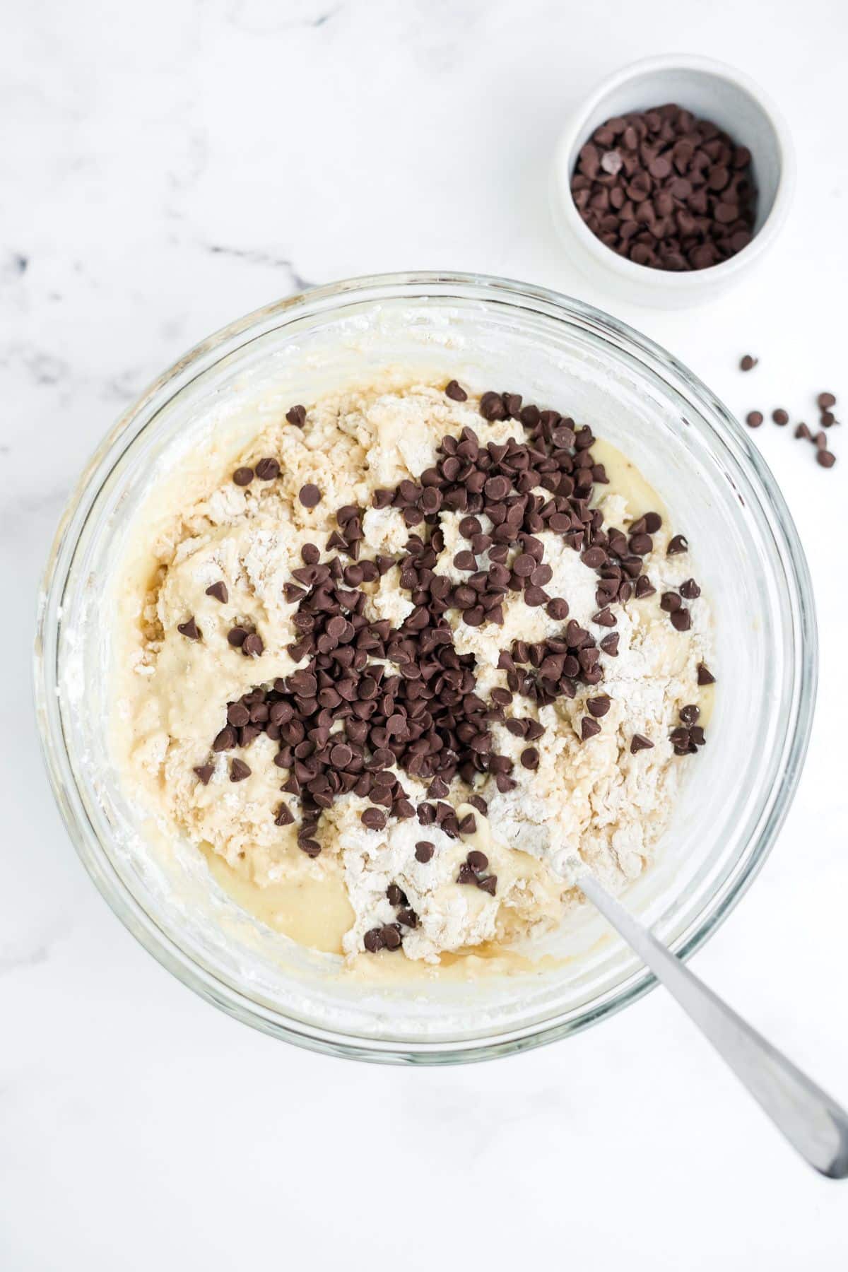 Batter mixed in a bowl with chocolate chips on topl.