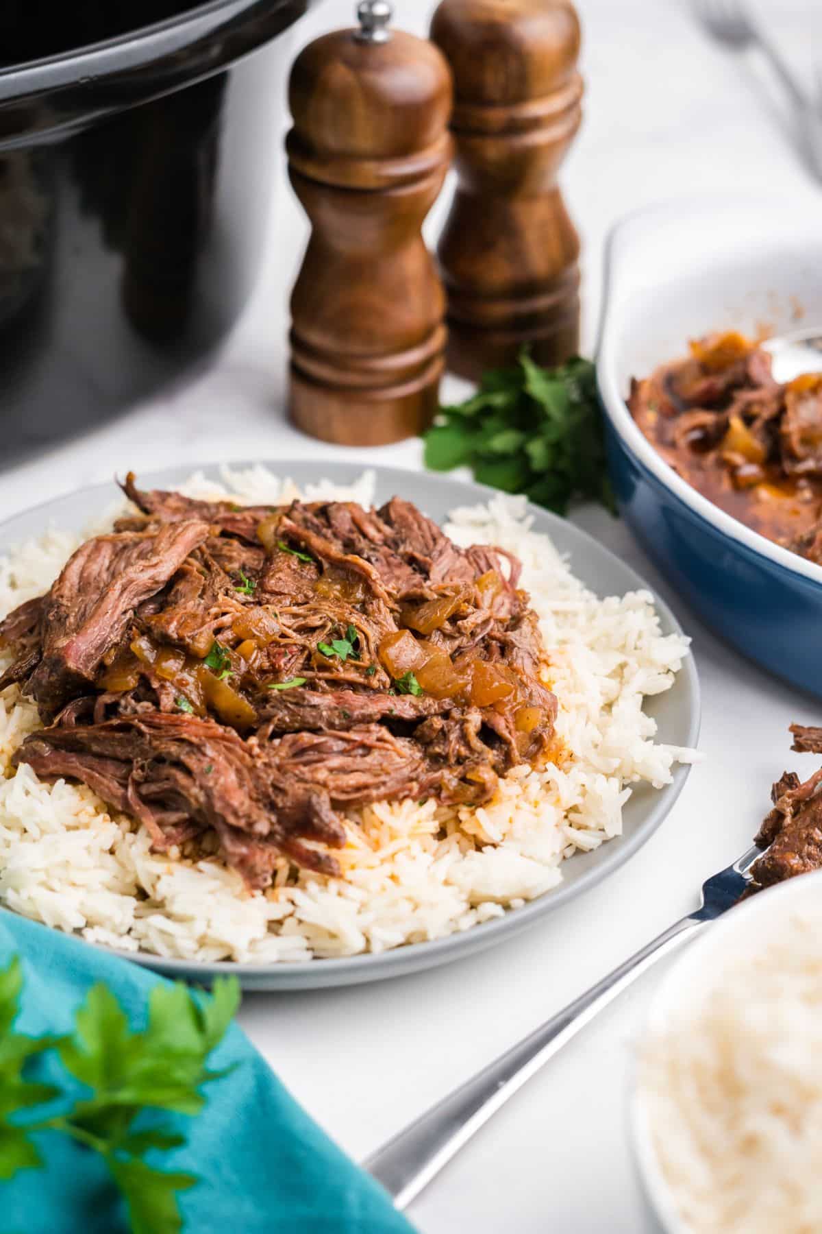 Crock pot skirt steak shredded and served over a plate of rice.