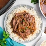Crockpot skirt steak shredded and served over a plate of rice.