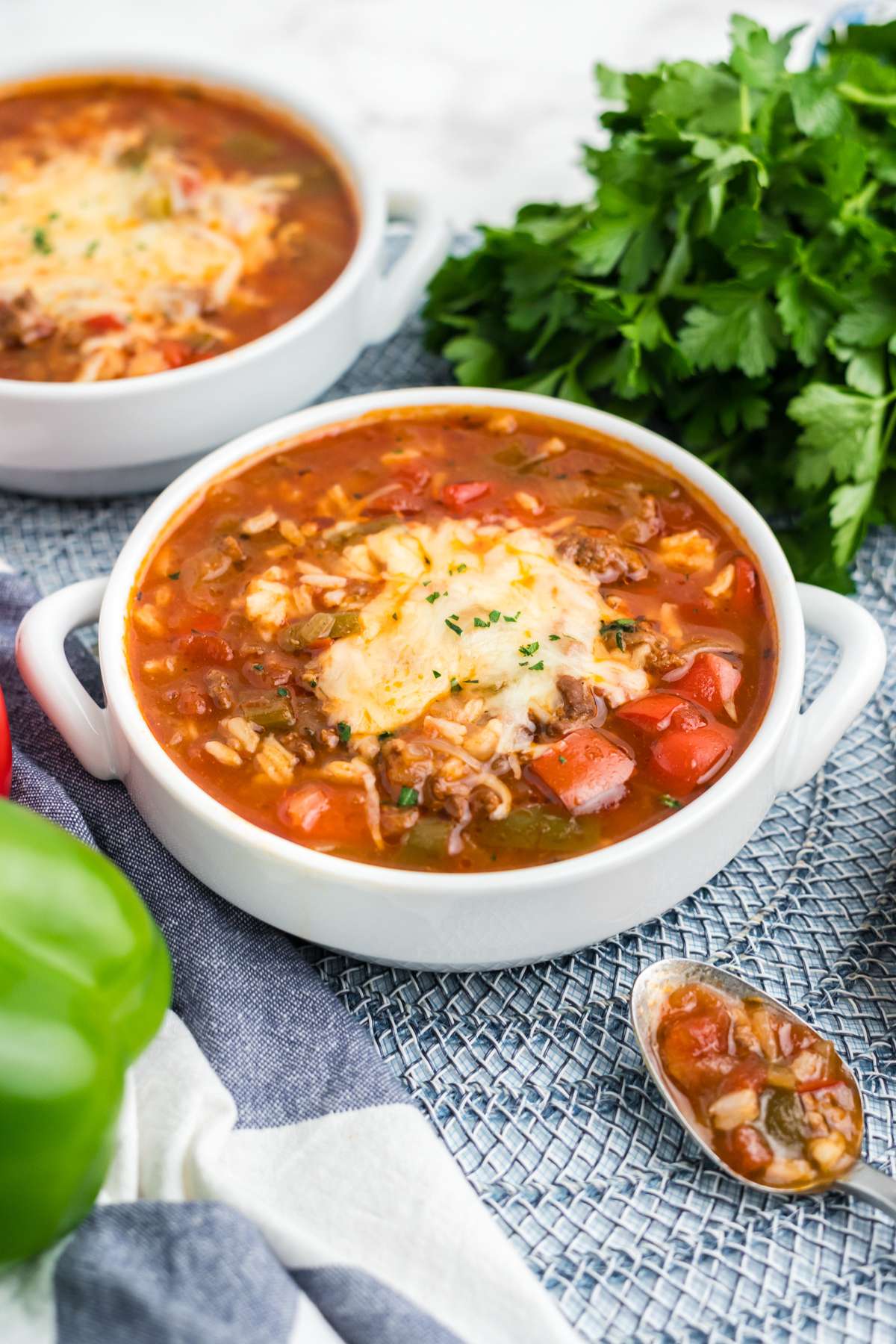 A bowl of stuffed bell pepper soup on a table with another in the background.