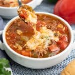 A spoon lifting up a bite of slow cooker stuffed pepper soup.