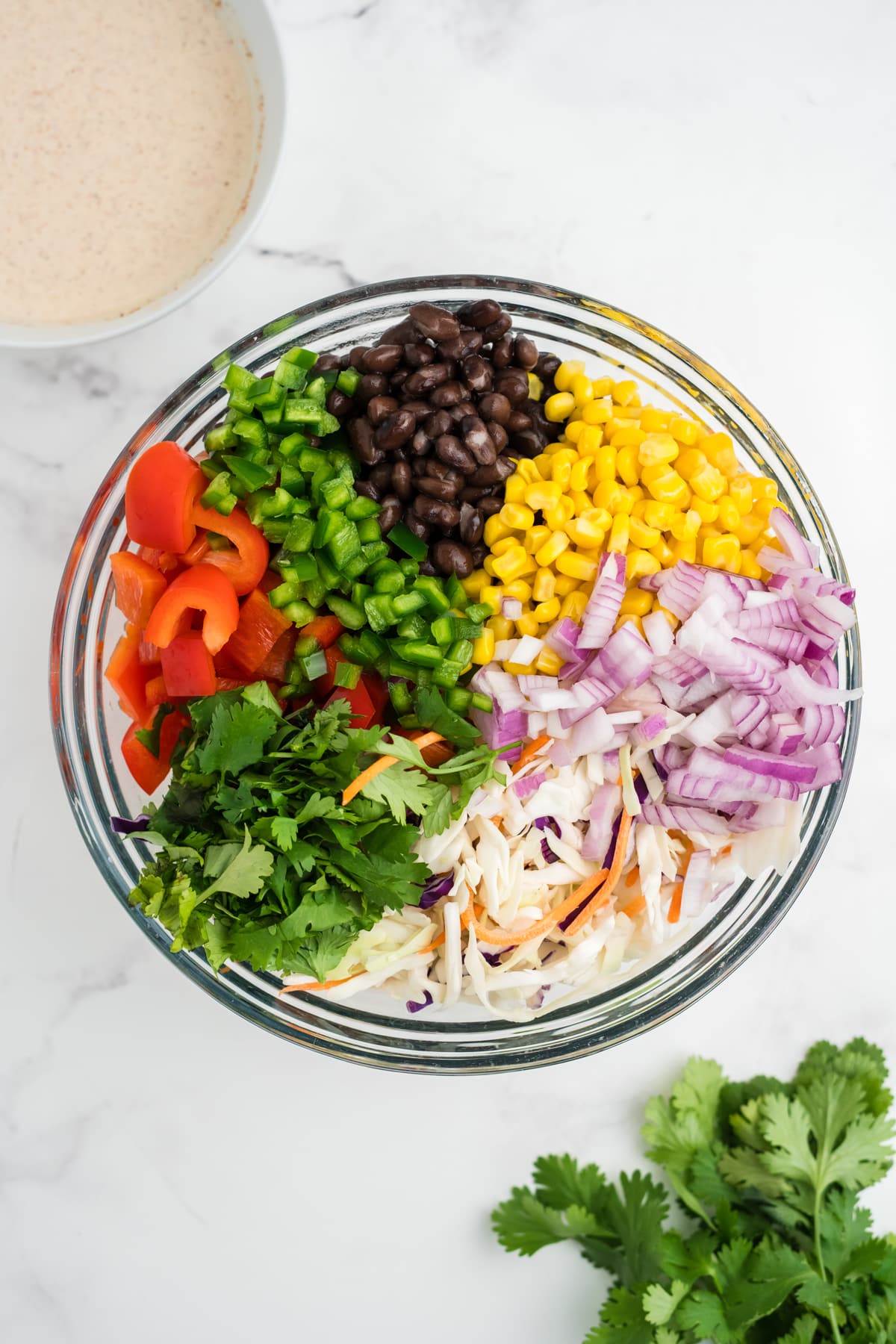 An image of ingredients for southwestern coleslaw in a bowl, pinwheel style so you can see all the ingredients.
