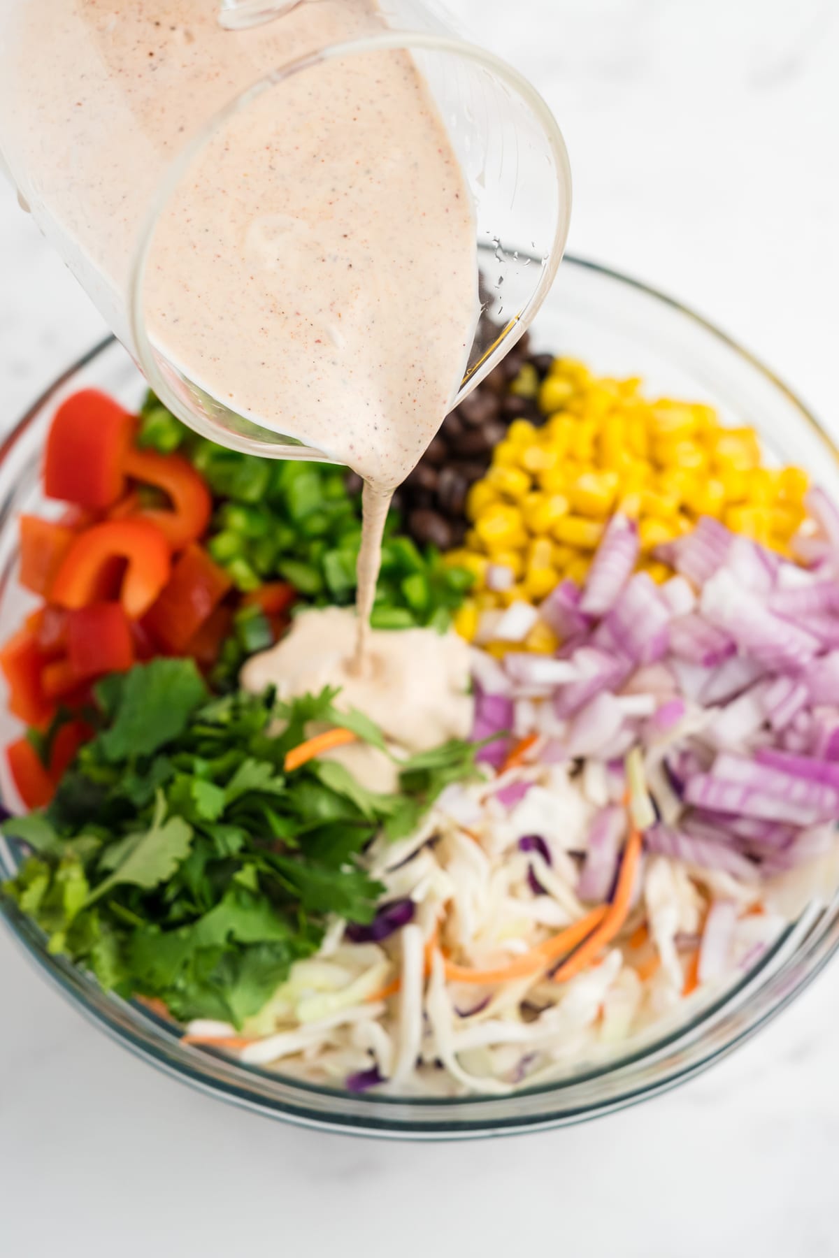 Southwest Colelsaw dressing being poured over southerwestern style coleslaw.