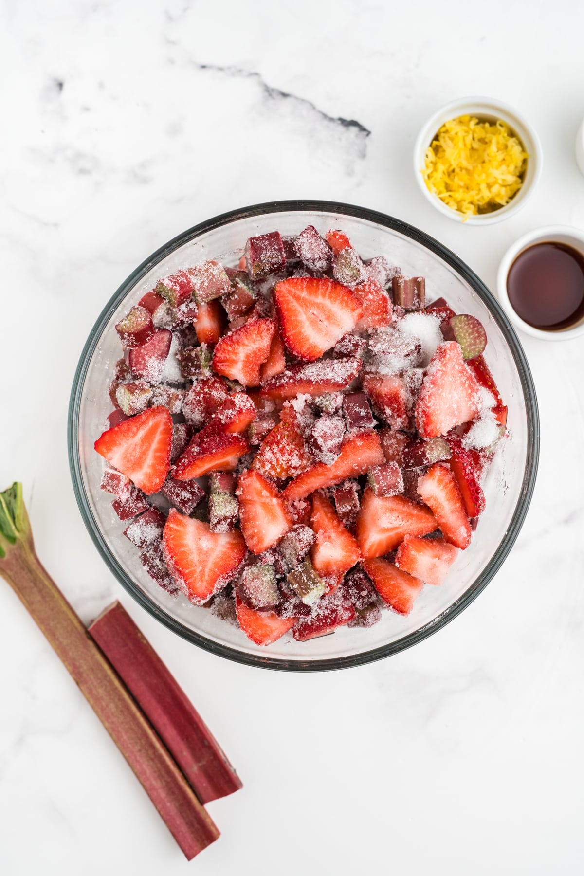 An image of strawberries and rhubarb coated in sugar before making jam.