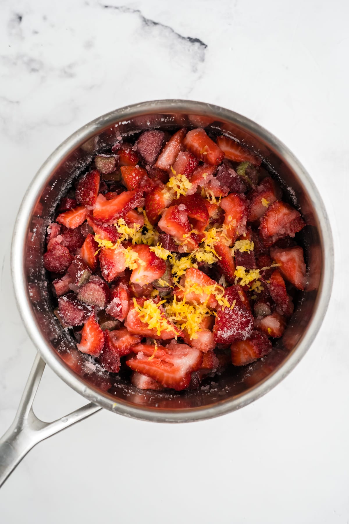 An image of ingredients for strawberry and rhurbarb jam inside of a pan before cooking.