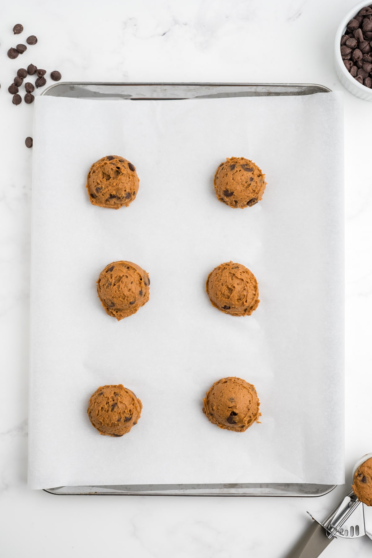 6 pumpkin cookies on a baking sheet before baking