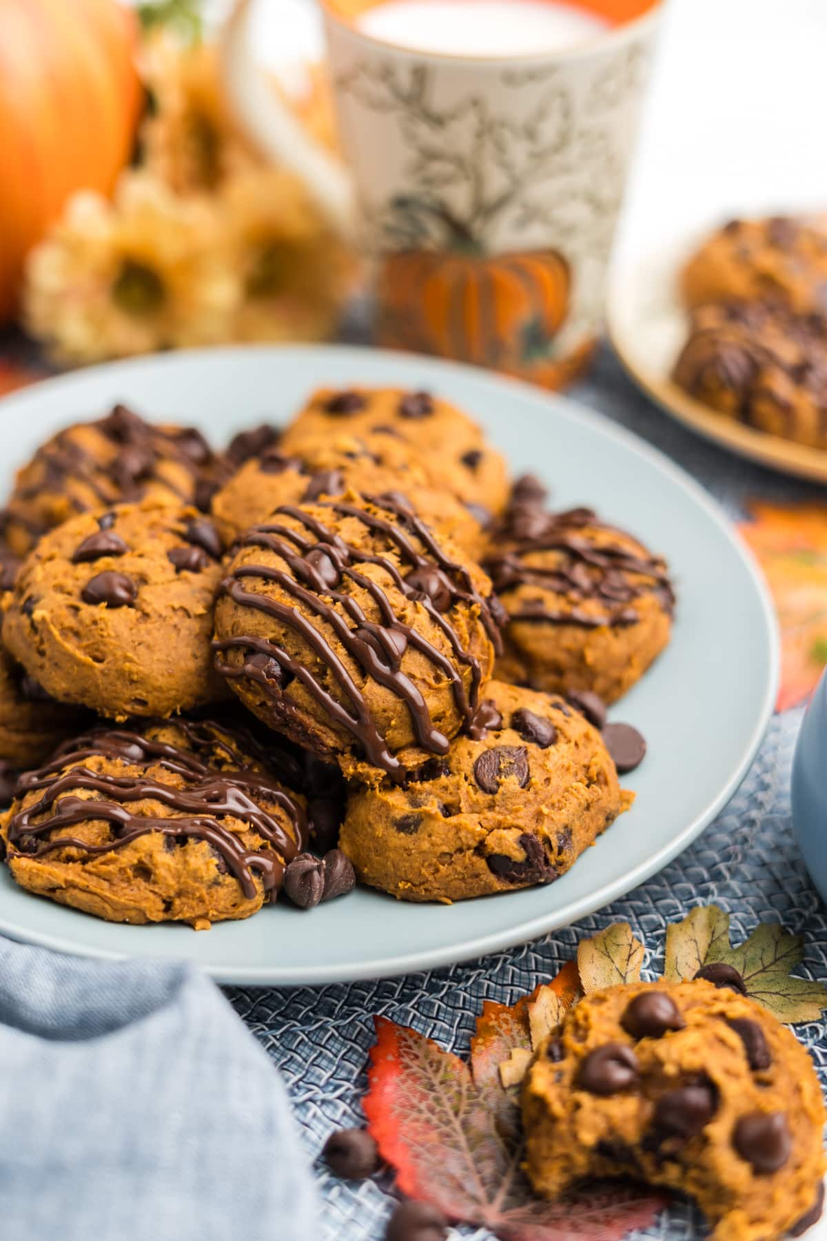 A plate of pumpkin chocolate chip cookies with chocolate drizzle.