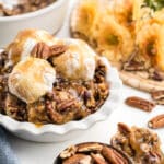 An image of hote pecan pie cobbler in a small white dish with 3 scoops of vanilla extract.