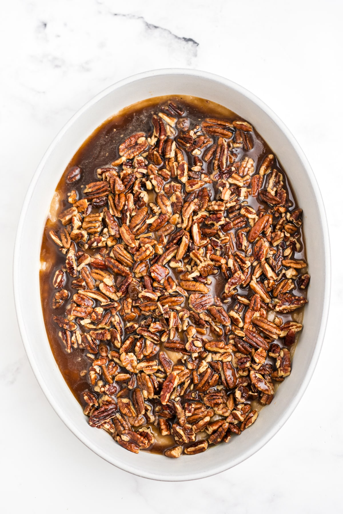 An overhead image of pecan pie cobbler in a casserole dish before being baked.