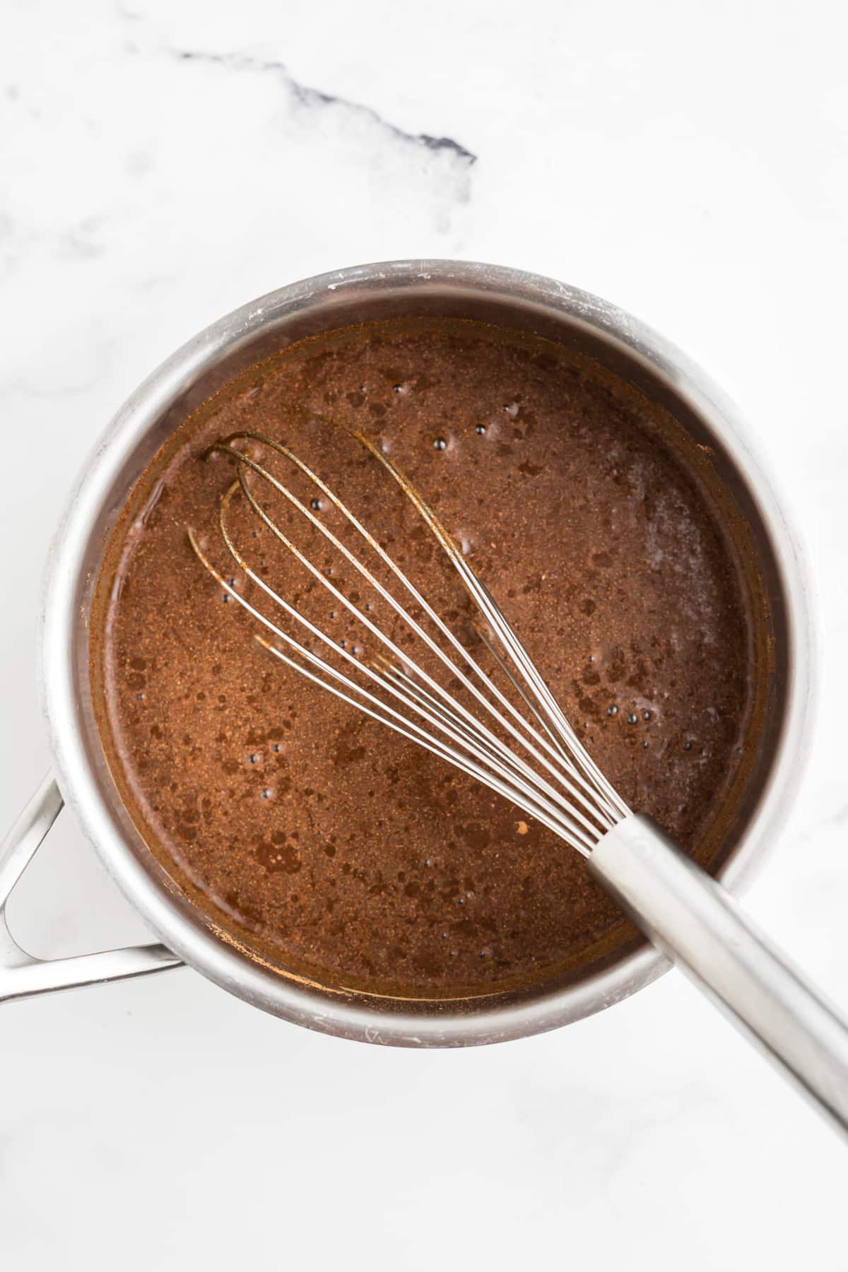 Ingredients for syrup being whisked in a saucepan. 