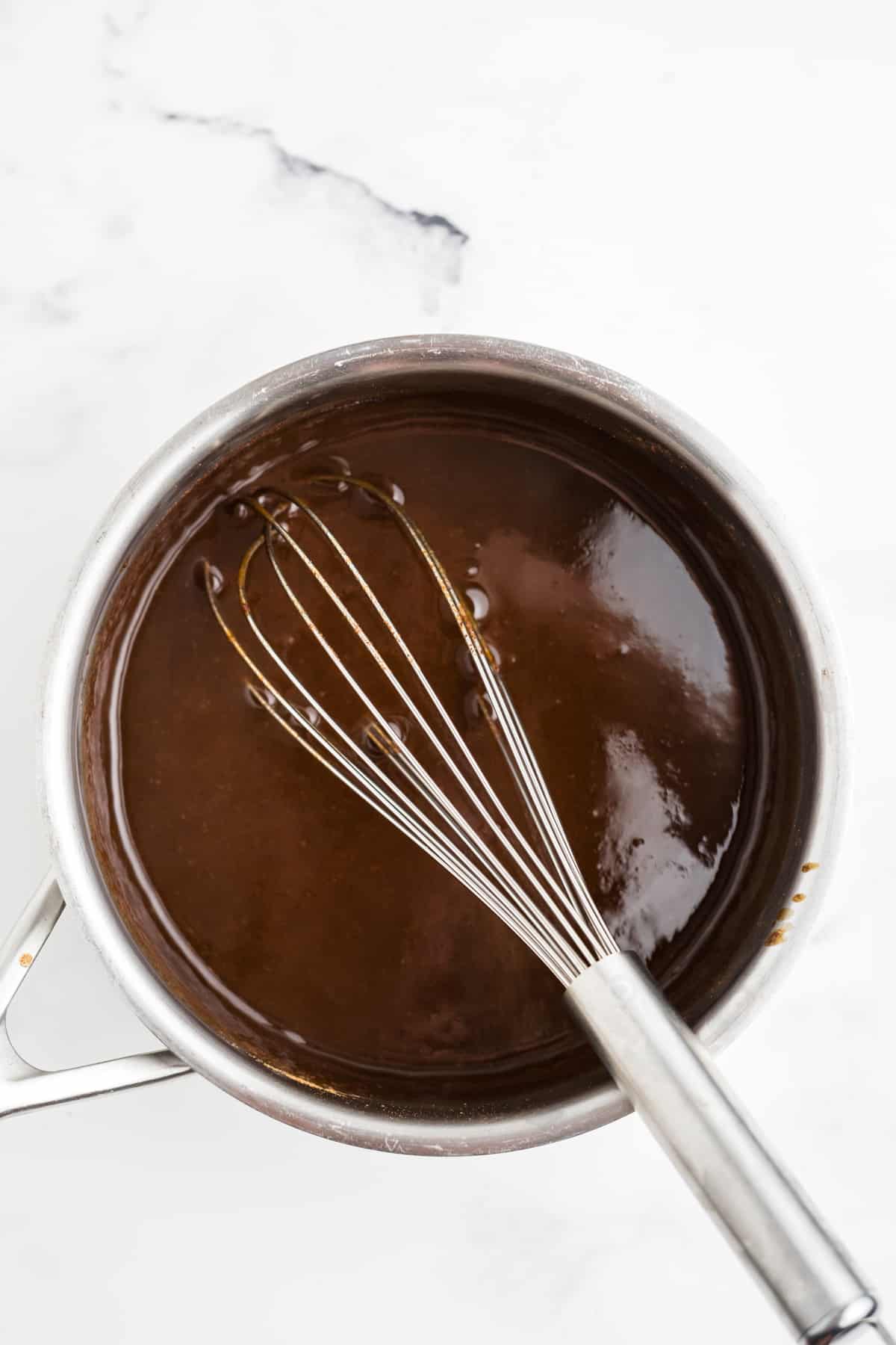 Homemade syrup being whisked in a saucepan. 