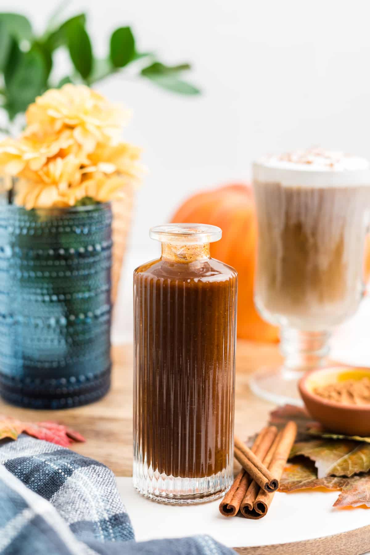 Homemade Pumpkin Spice Syrup in a syrup bottle with fall decor surrounding it. 