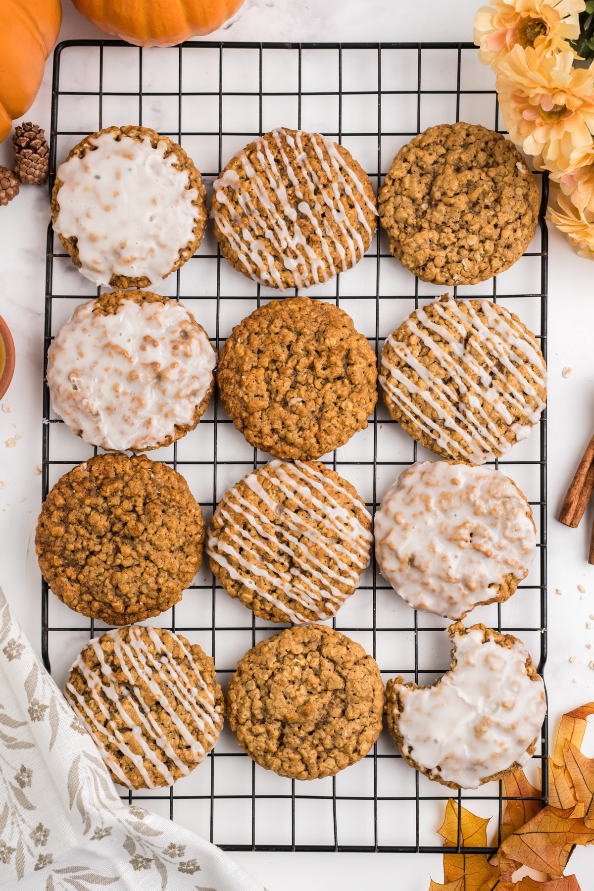 An overhead image of glazed pumpkin oatmeal cookies on a cooking sheet with fall decor around them. 