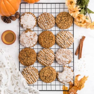 An overhead image of pumpkin oatmeal cookies on a cooking sheet with various types of glaze.