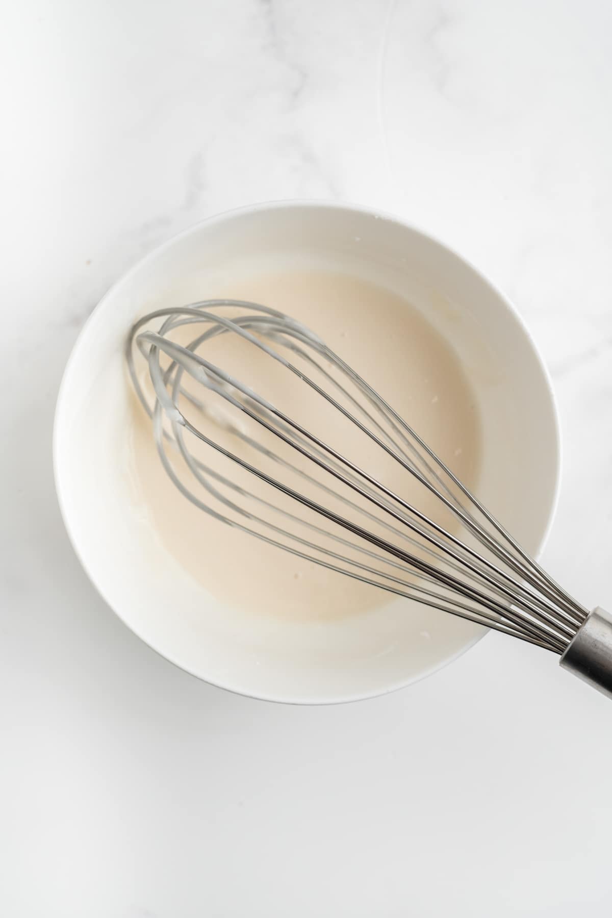 An overhead image of glaze being whisked in a bowl. 