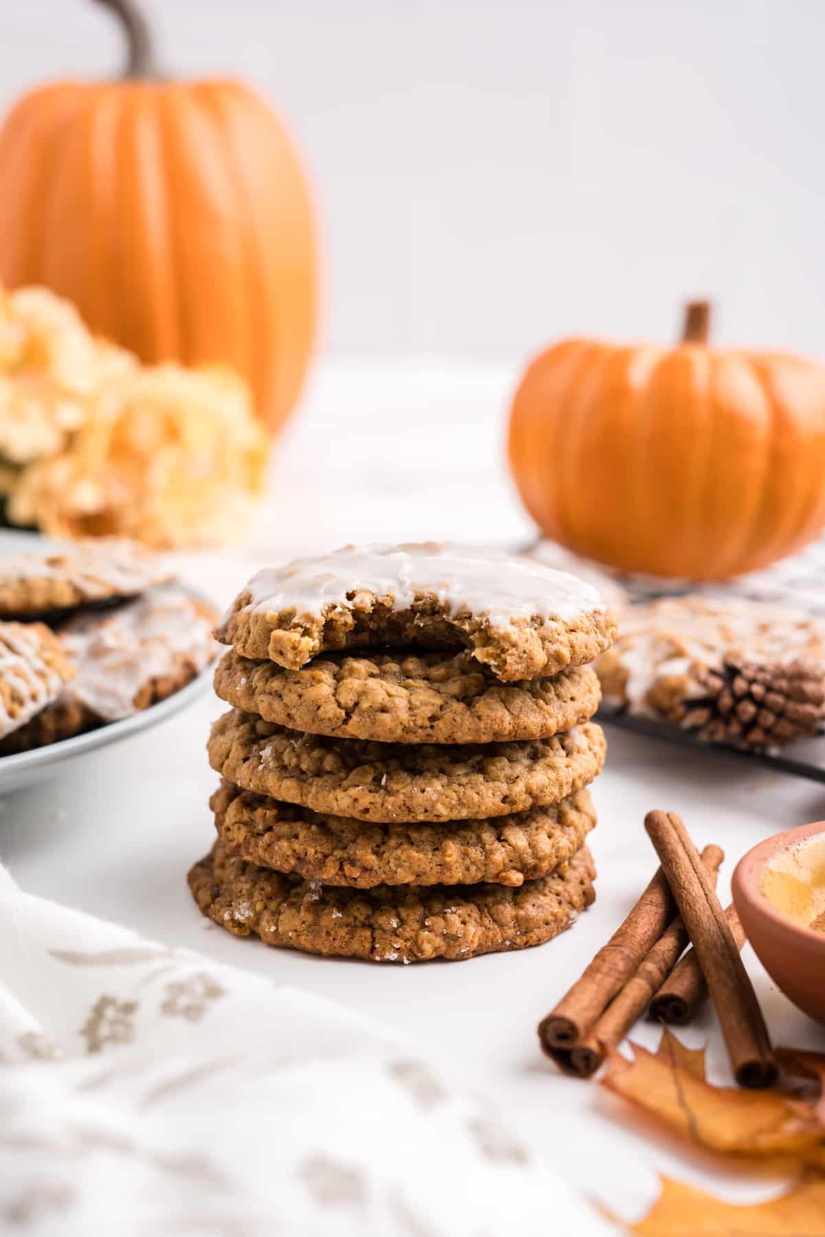 Stacked Pumpkin Oatmeal Cookies with glazed cookie with a bite on top. 