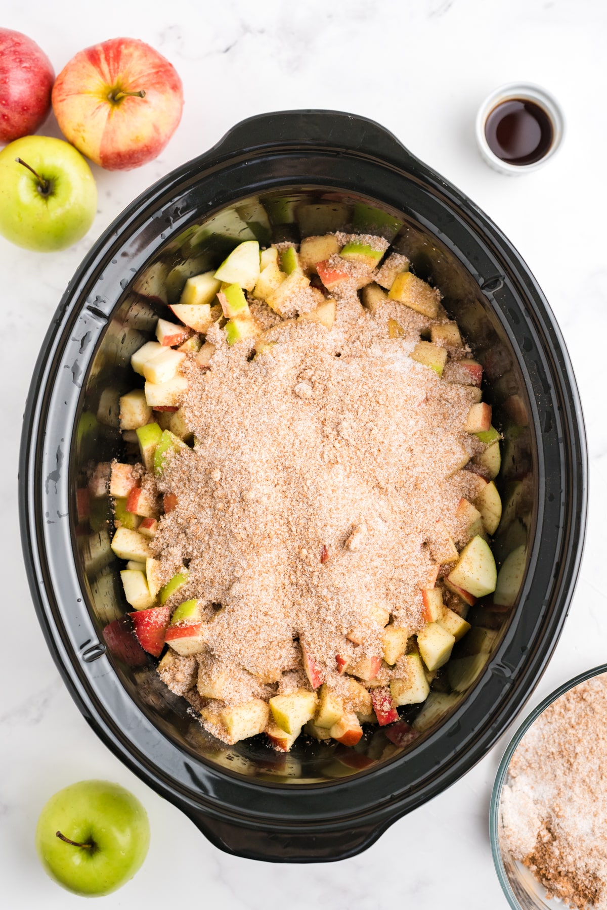 diced apples in the bottom of a slow cooker with cinnamon and sugar on top