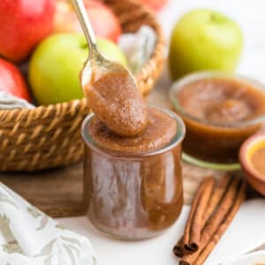 Apple Butter in a glass jar with a gold spoon scooping.
