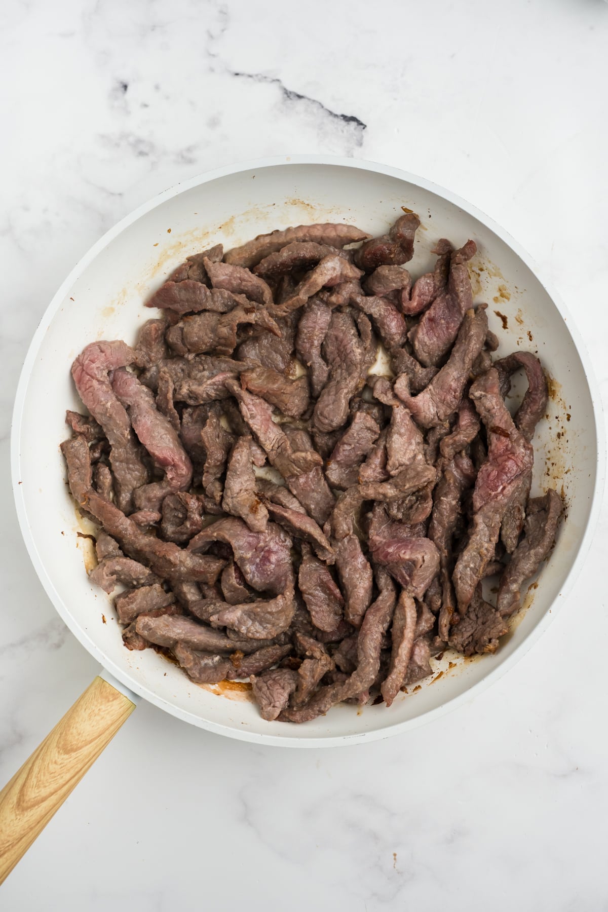 Cooked sliced beef in a skillet.