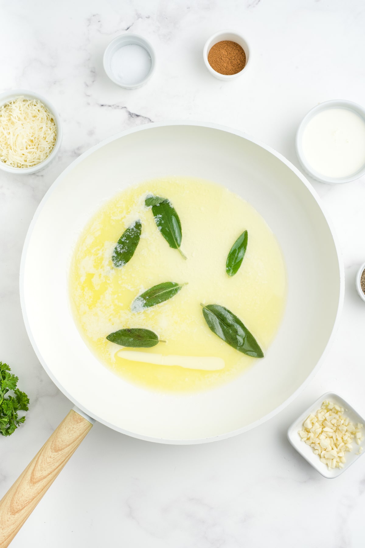 Sage leaves added to the melted butter in a skillet. 