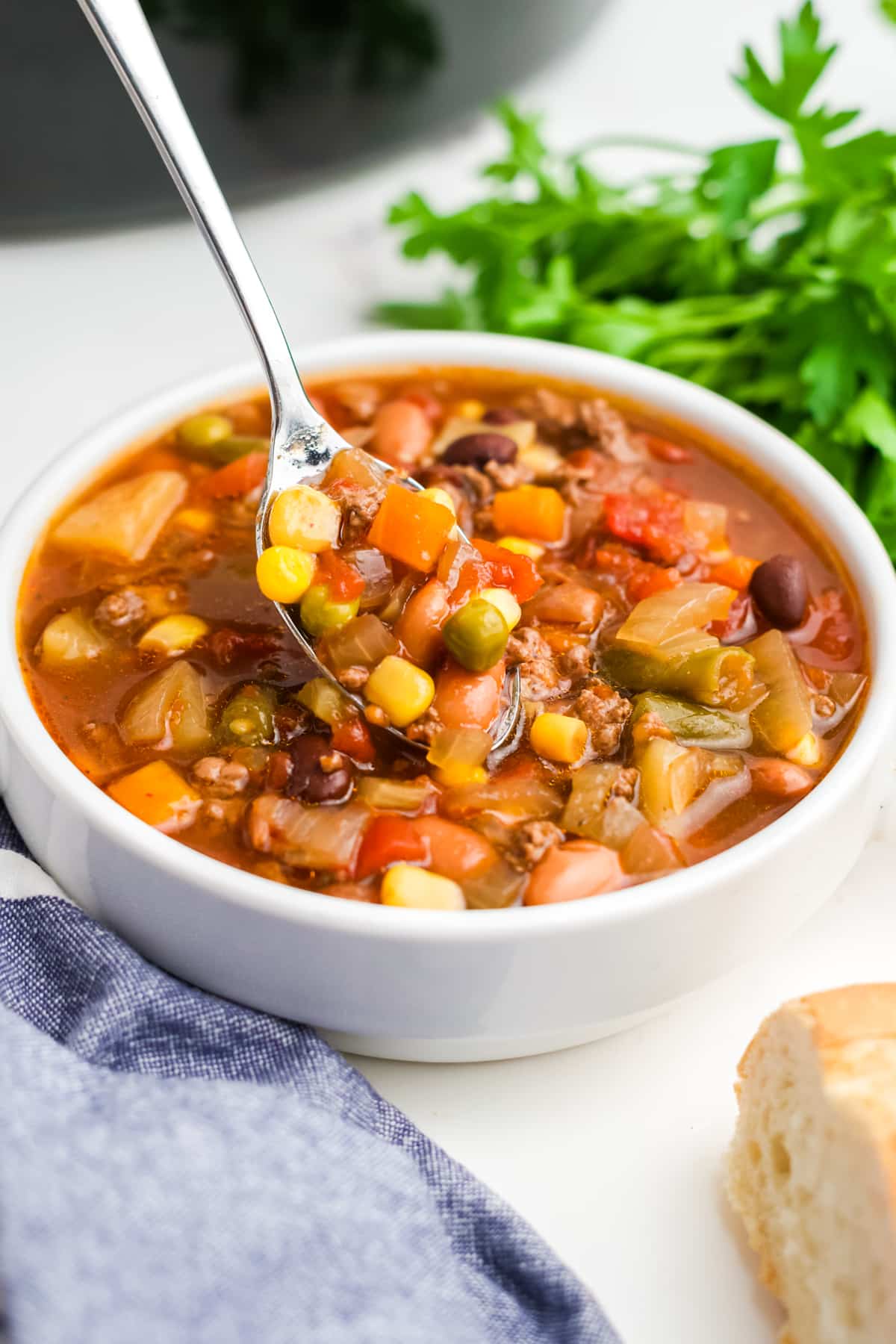 A white bowl filled with crock pot cowboy soup and a spoon lifting a bite up. 