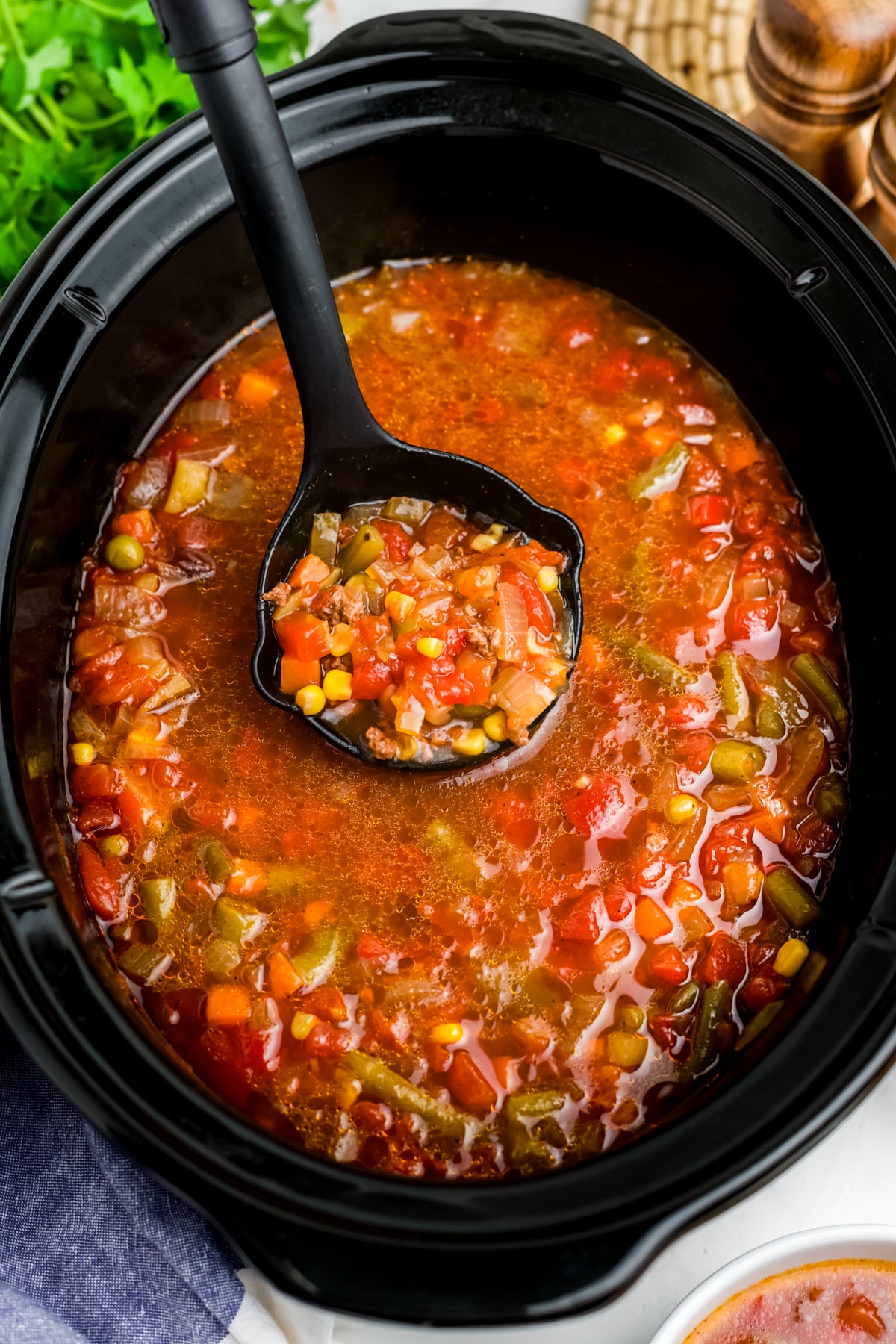 Cooked crock pot cowboy soup being ladled out of the slow cooker.