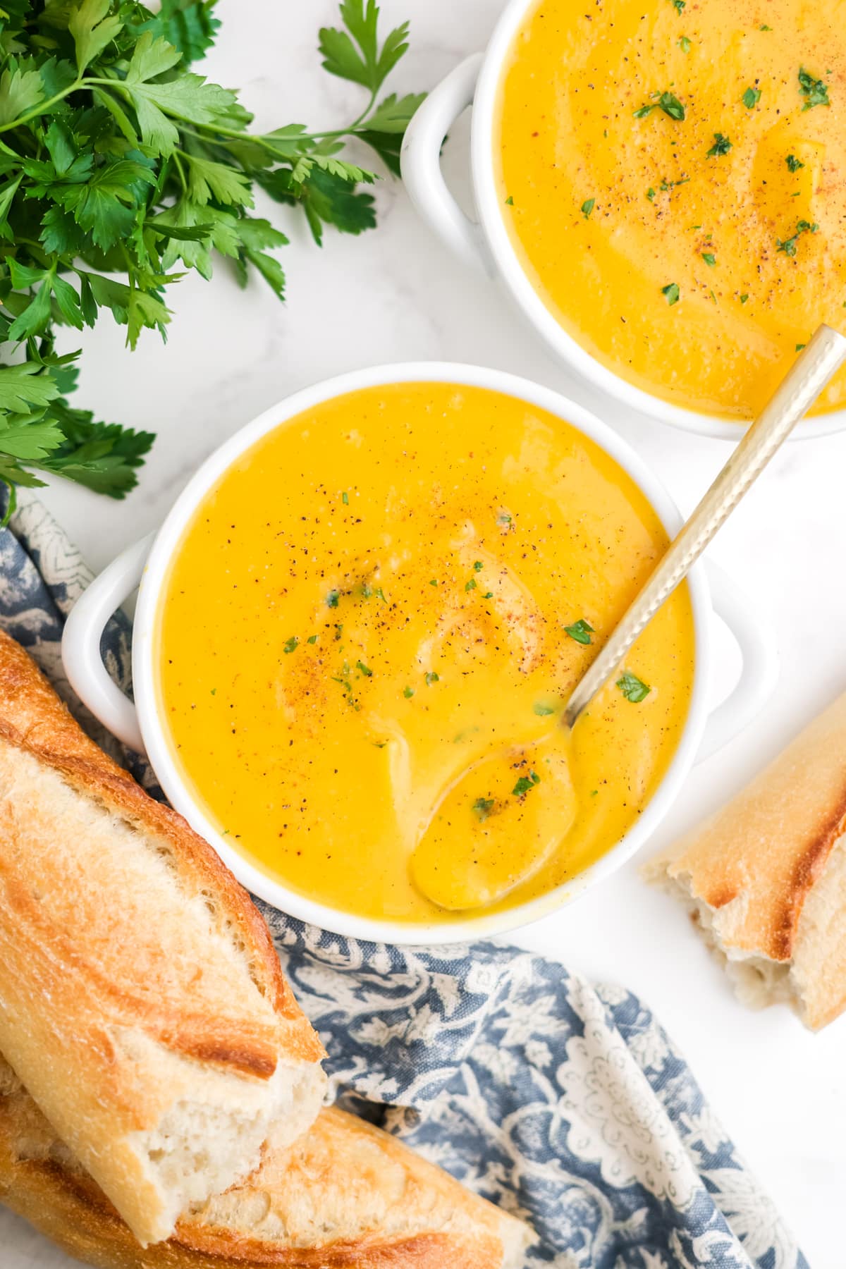 Two bowls of roasted butternut squash soup with a spoon in one of the bowls. 