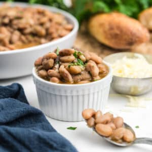 A small bowl of slow cooker pinto beans with a spoon of them to the side.