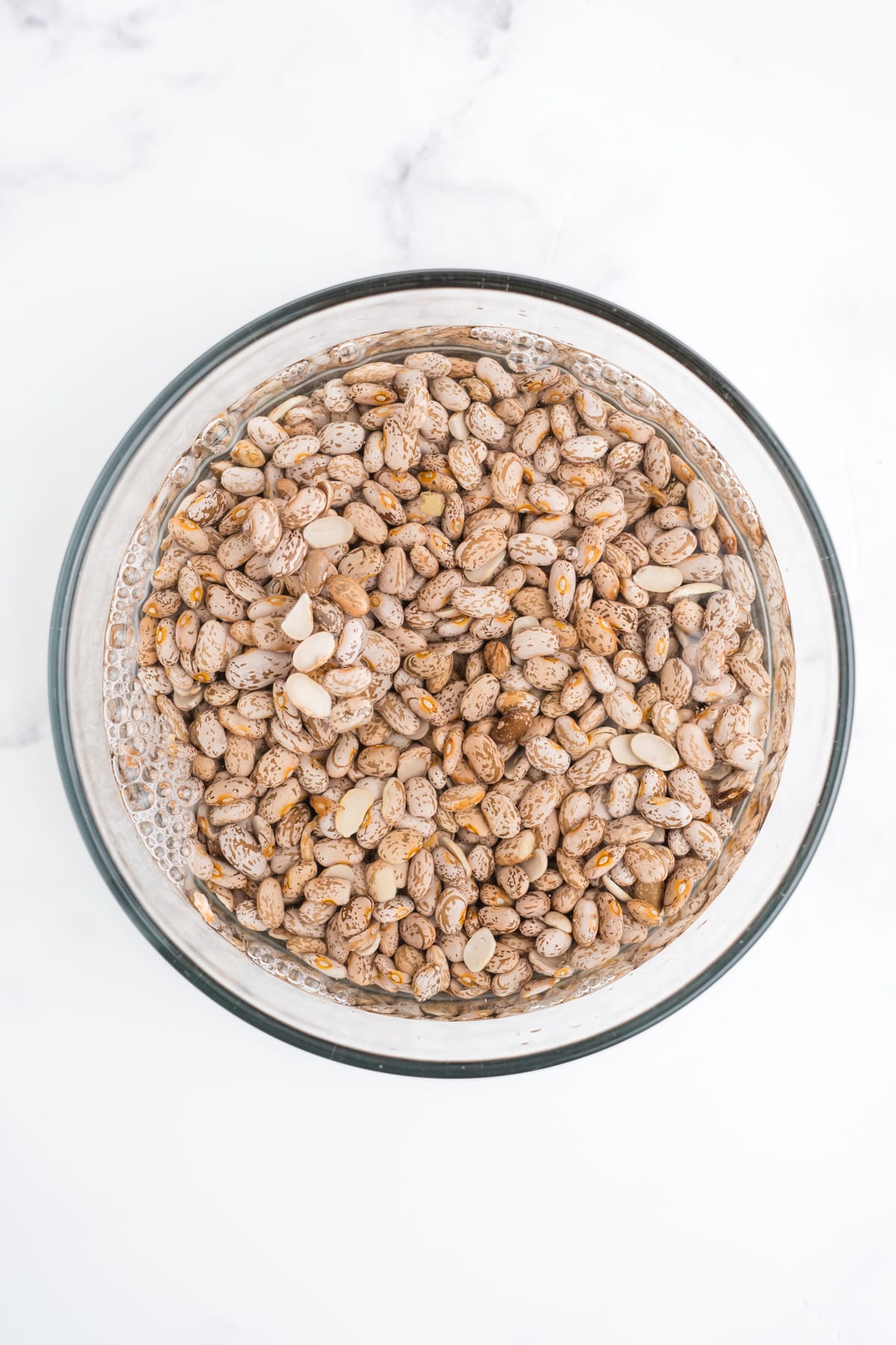 Dry pinto beans in a glass bowl.