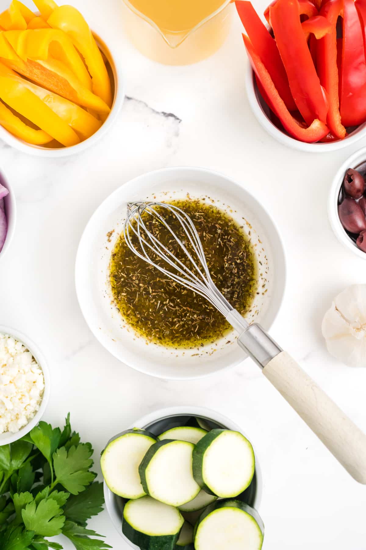 Sauce for Greek chicken in a bowl with a whisk.