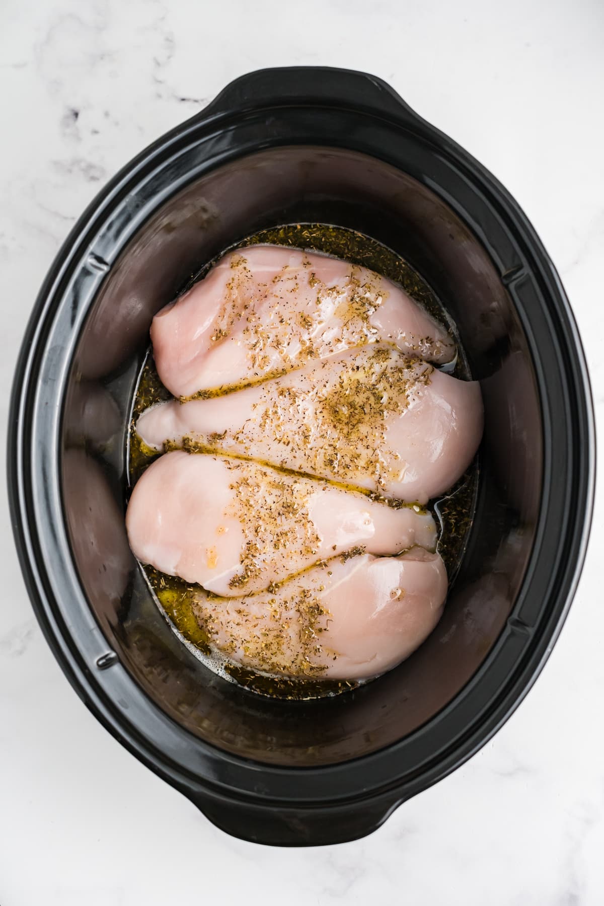 Chicken breasts and sauce in a slow cooker.