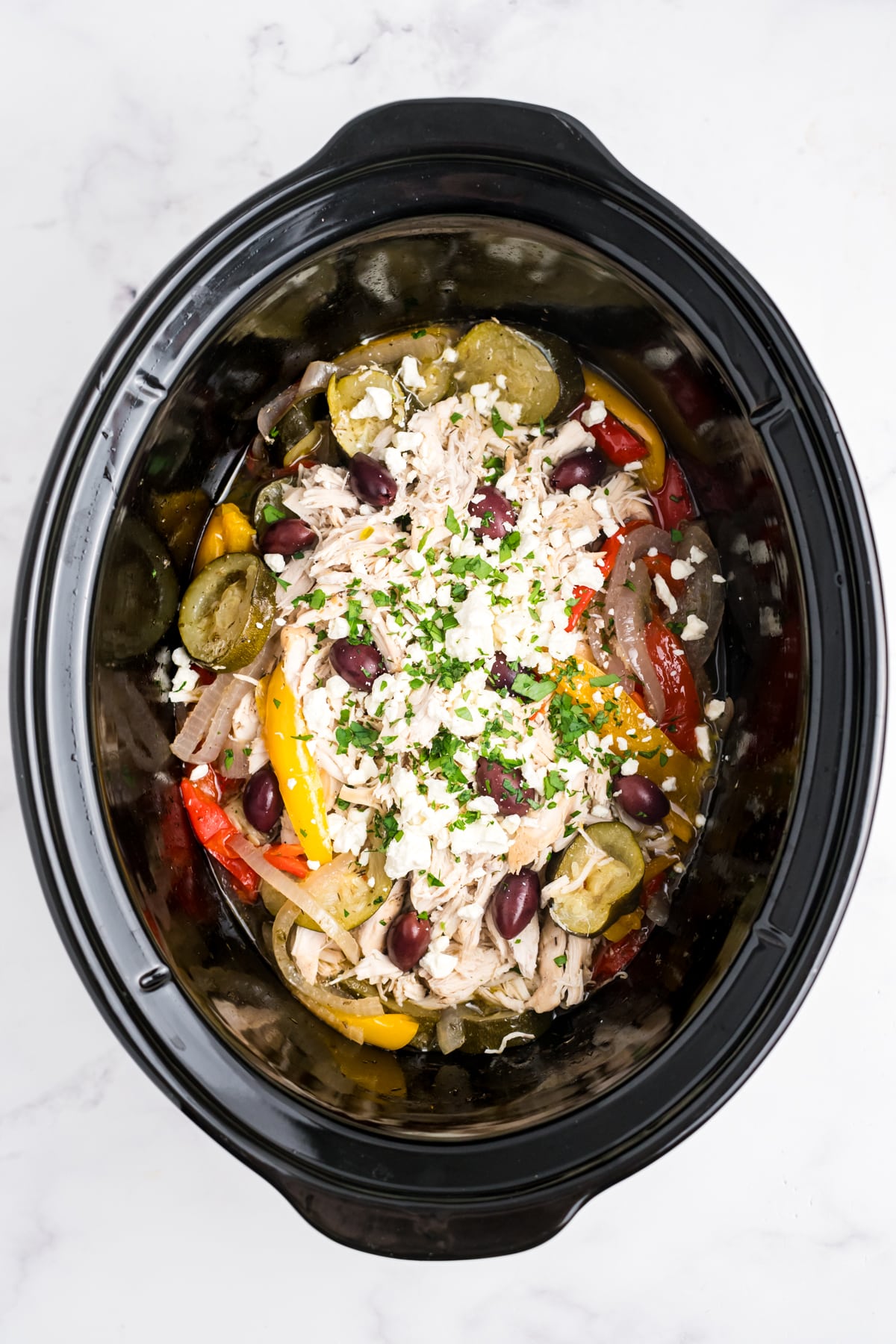 Shredded chicken, olives and feta cheese added back into the slow cooker. 