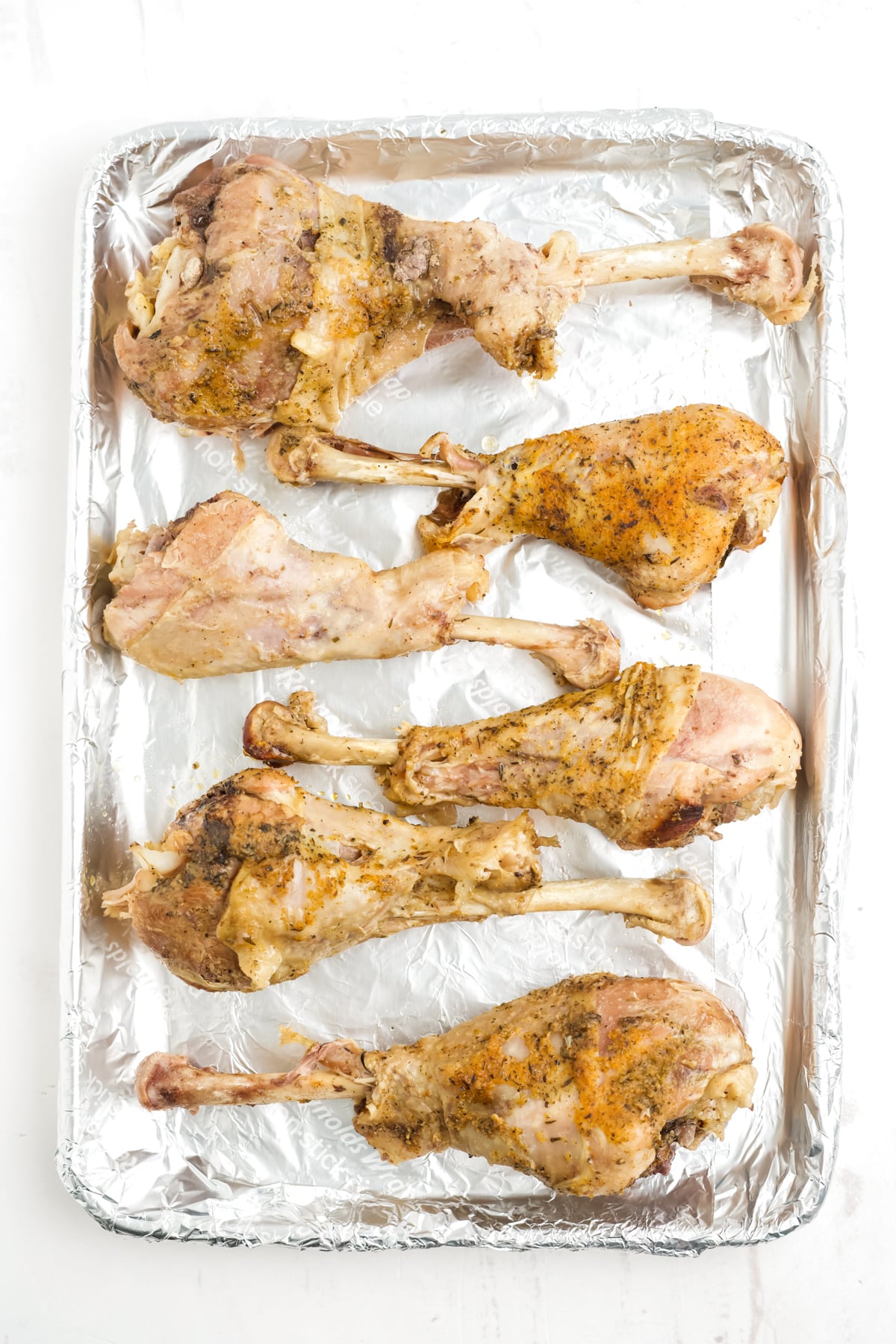 Boiled turkey legs on a baking sheet.