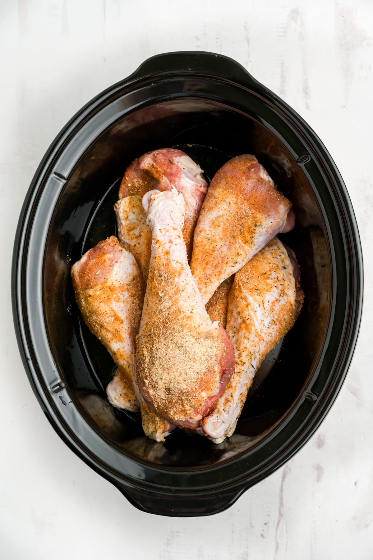 Raw seasoned turkey legs in the slow cooker.