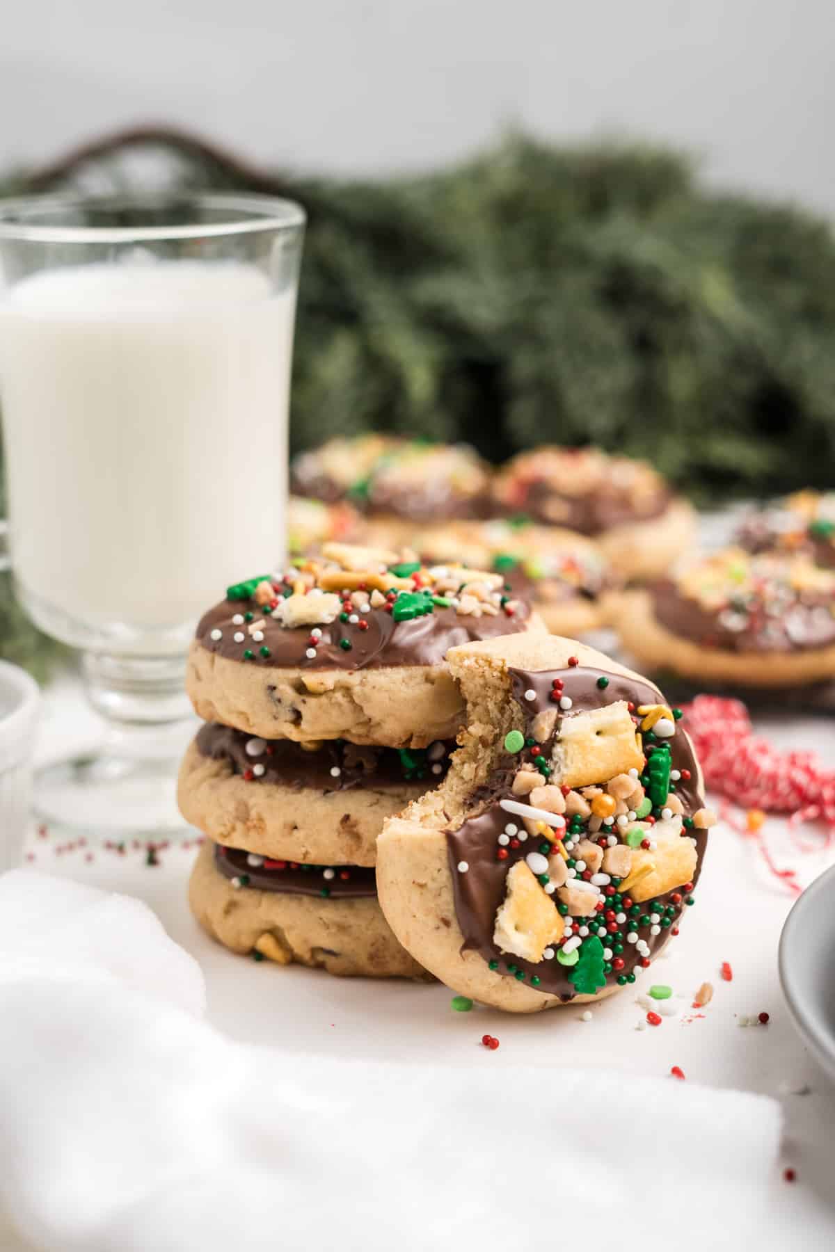 A stack of Christmas crack cookies with a bite taken from one leaning up against the stack. 