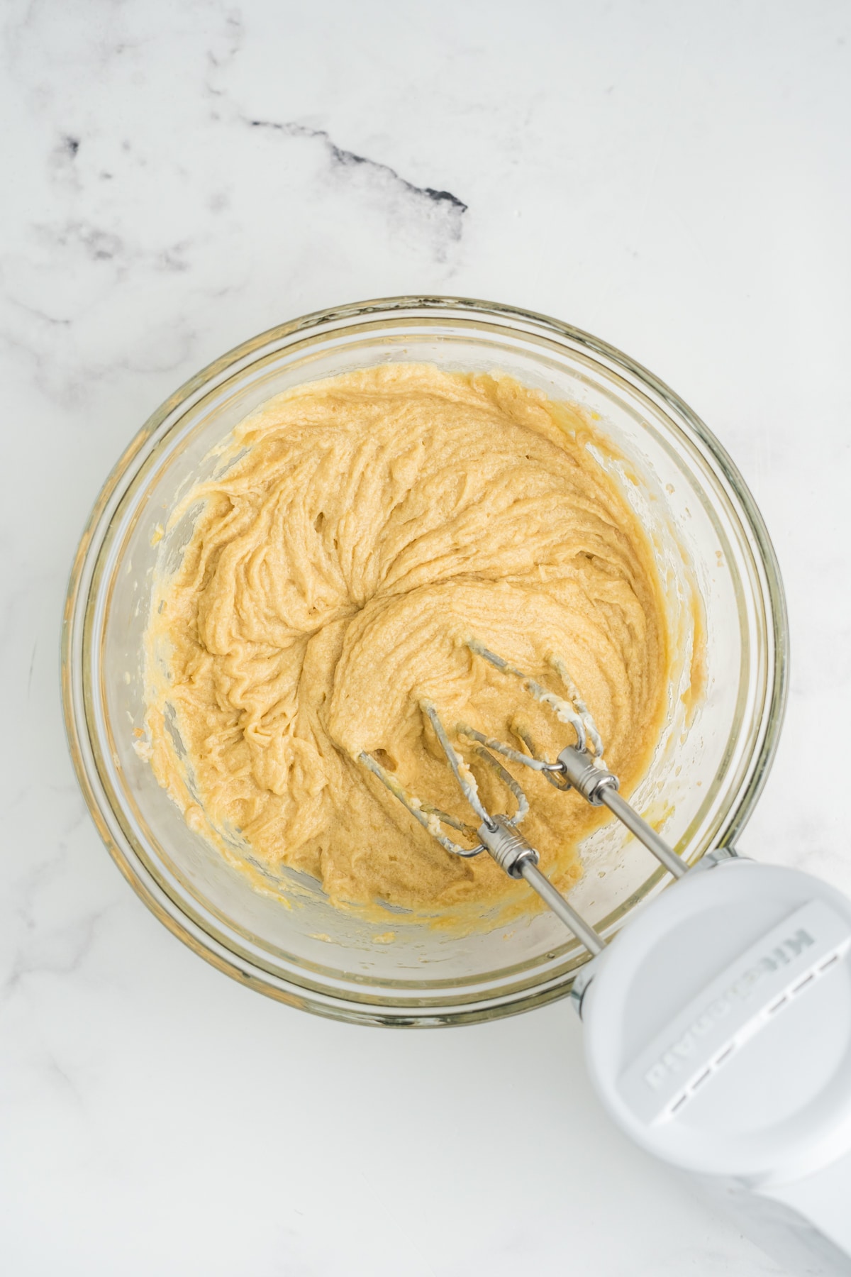 Wet ingredients mixed together with an electric mixer in a bowl.