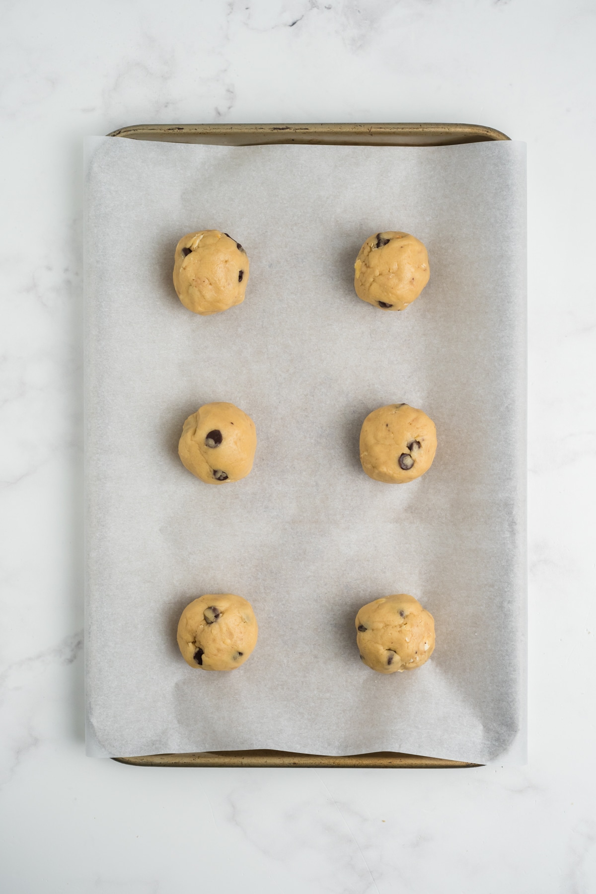 Raw cookie dough balls on a baking sheet.