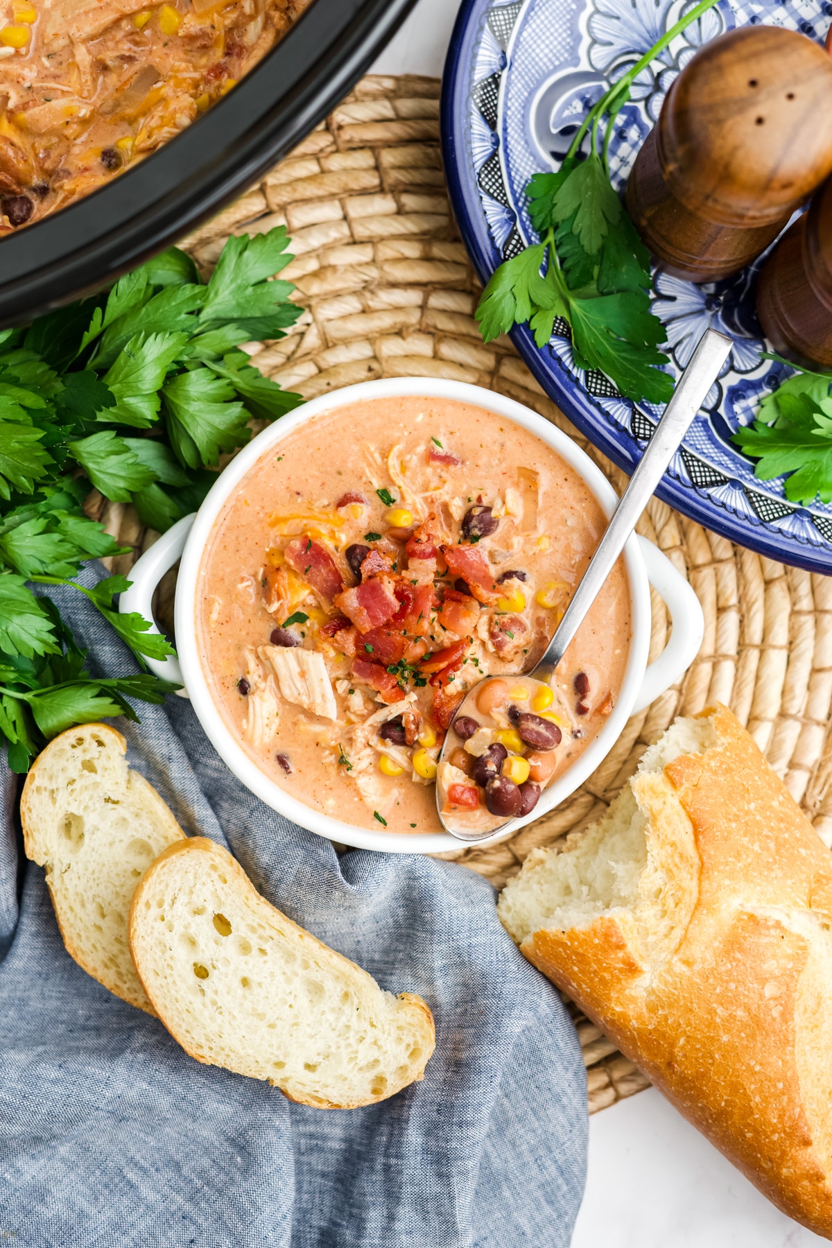 Crack chicken chili in a bowl with a spoonful and some bread to the side. 