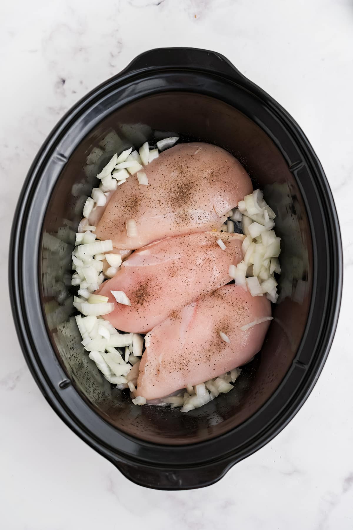 Chicken and onions added to the slow cooker.