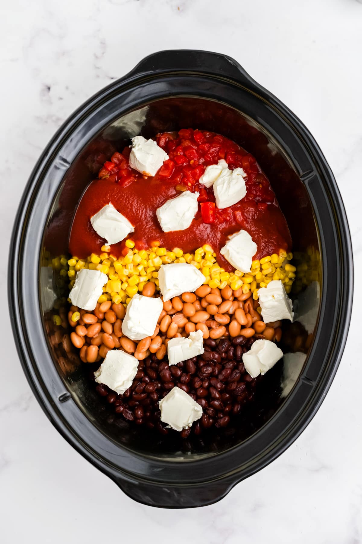 Beans, corn, tomatoes and cream cheese added to the slow cooker.