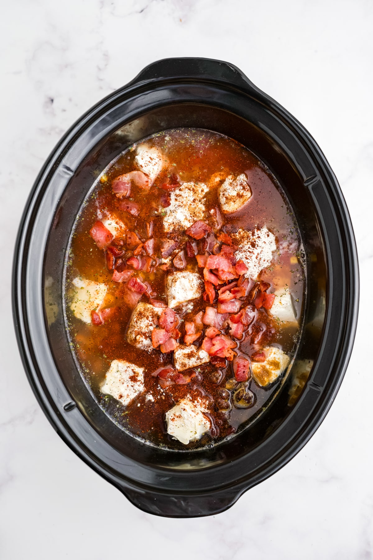 Chicken broth and bacon added to the slow cooker.